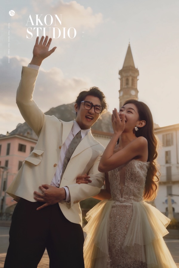 Couple laughing in the piazza by the Varenna bell tower during their photoshoot