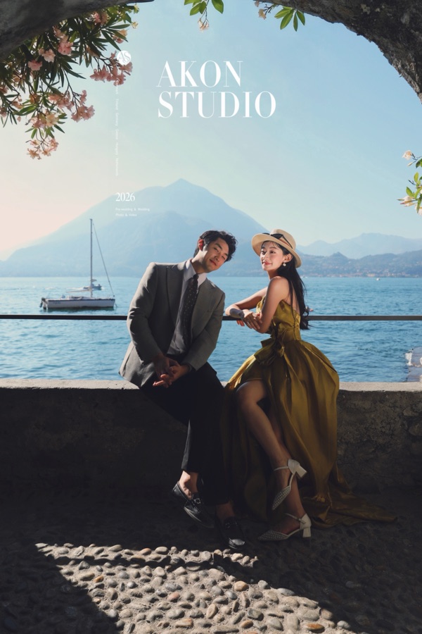 Bride and groom under a stone arch with a boat on Lake Como