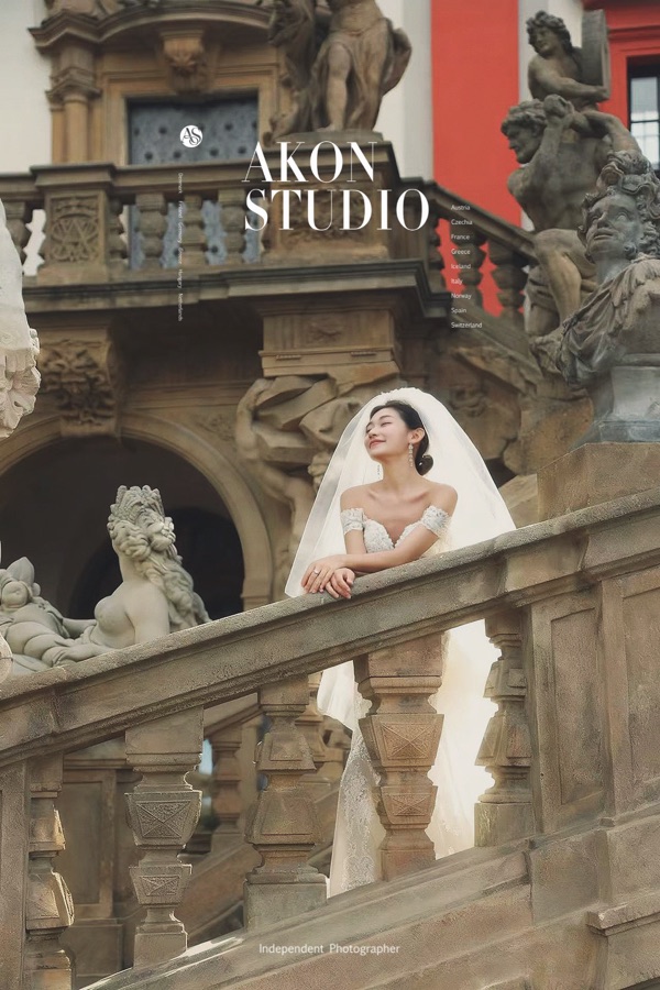 Bride in an off-shoulder gown with a long veil on a baroque stone staircase lined with carved statues